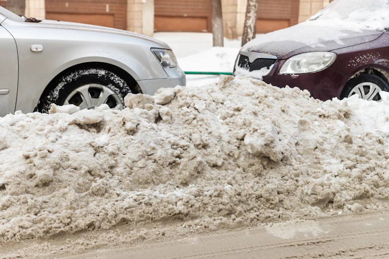 two parked cars trapped in by piled snow
