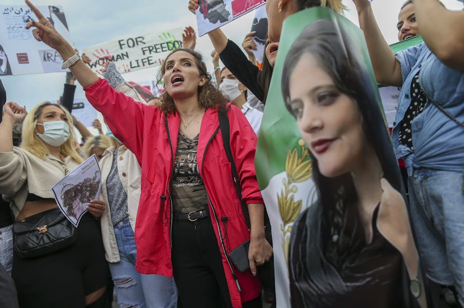Women shouting slogans  while holding a picture of a young woman.