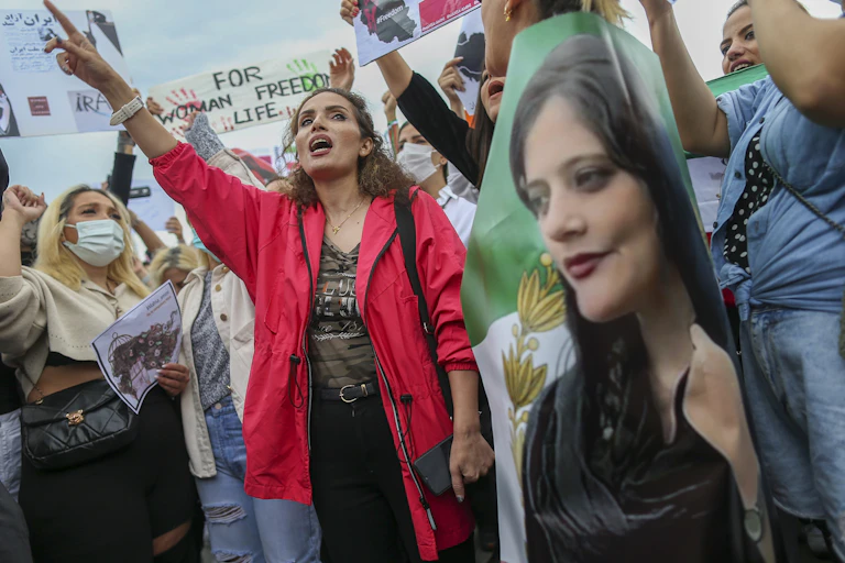 Women shouting slogans while holding a picture of a young woman.