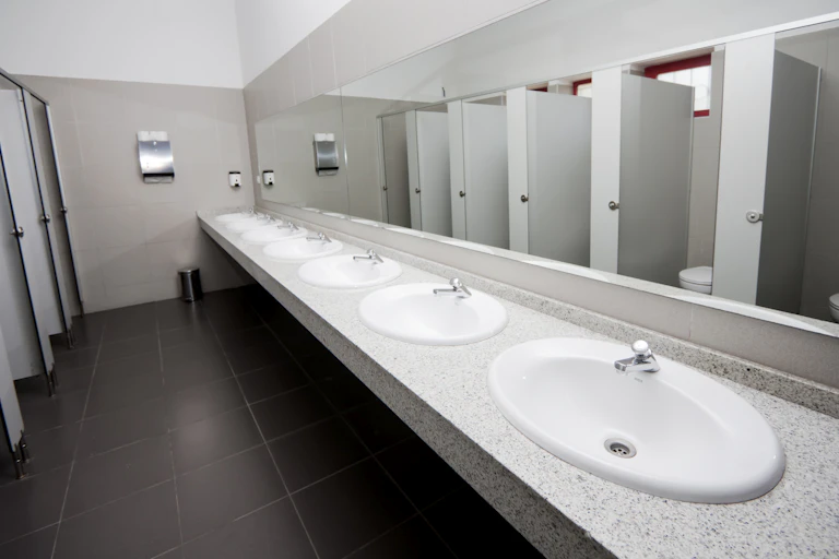 A row of sinks and bathroom stalls in a public bathroom.