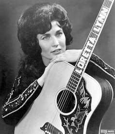 Black and white photo of woman posing with guitar.