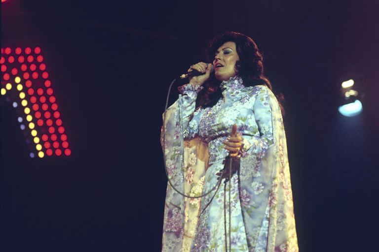 Woman sings into microphone during performance.