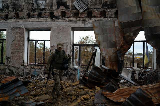 A Ukrainian serviceman walking through rubble in the eastern town of Lyman