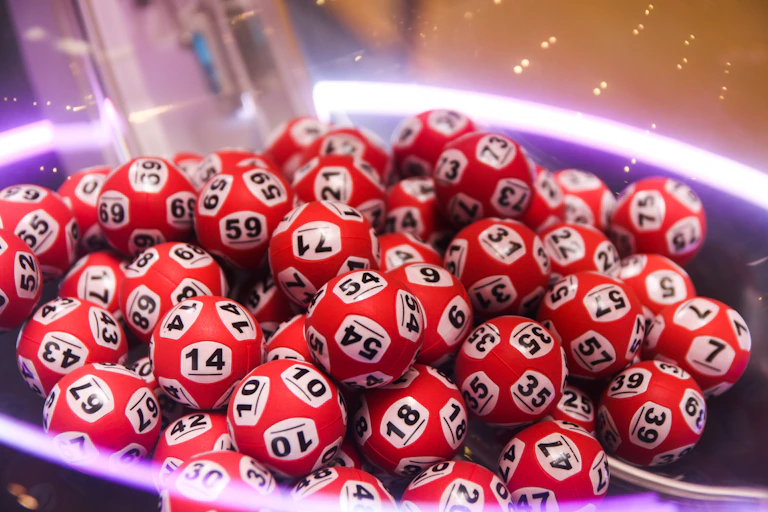 A close-up view of a pile of red lottery balls, randomly numbered