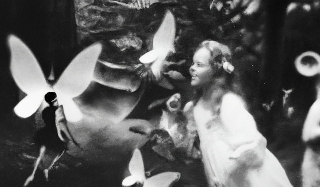 A grayscale pastiche of fairies and fantastical figures surrounding a little girl