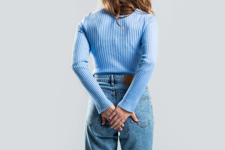 A woman clasps her butt as if in pain.