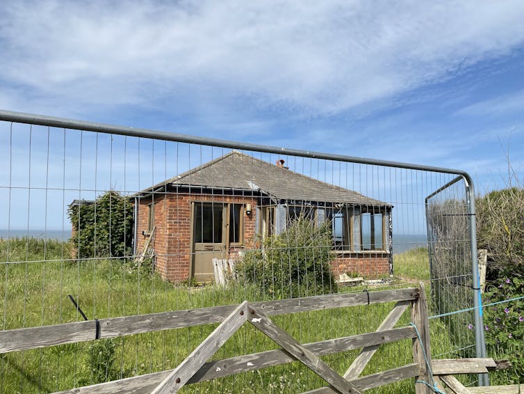 An abandoned building behind a metal fence.