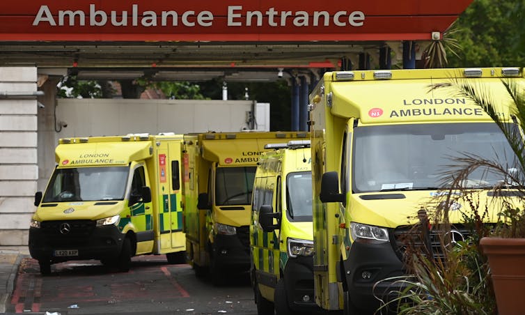 A number of ambulances waiting under a sign 'Ambulance Entrance'.