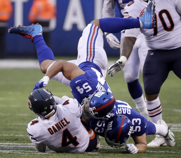 American footballer upsidedown during tackle.