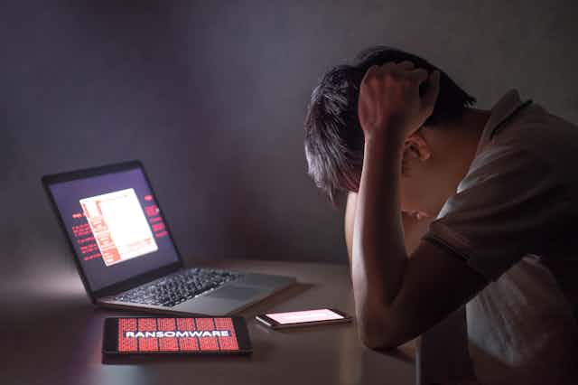 Hombre abatido con la cabeza entre las manos frente a un ordenador.