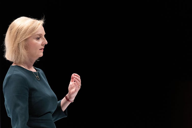 Liz Truss giving a speech against a black background