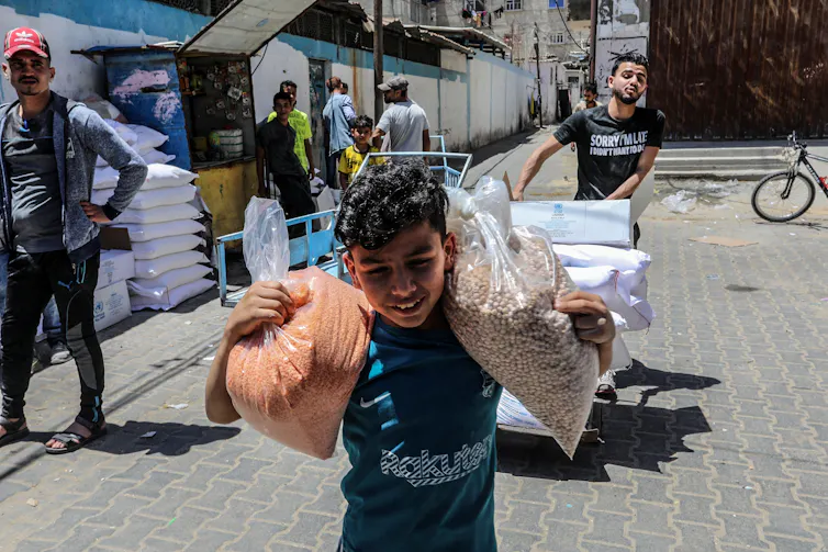 A boy carries sacks of food