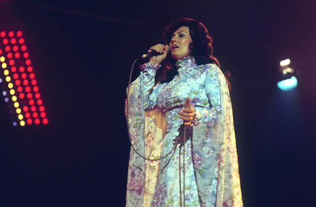 Una mujer canta con un micrófono durante una actuación.