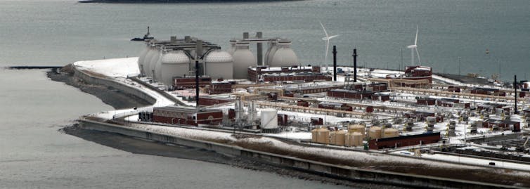 Aerial view of water treatment tanks and gas digesters on a peninsula surrounded by ocean