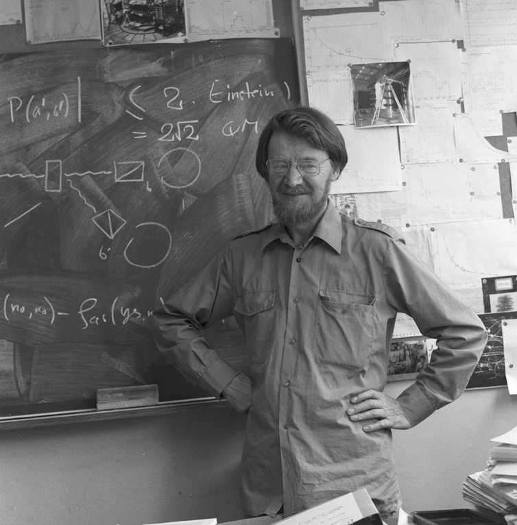 A photo of John Stuart Bell in front of a chalkboard.