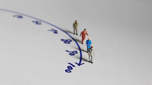 Minature people walking along a curved arrow with numbers denoting different ages.