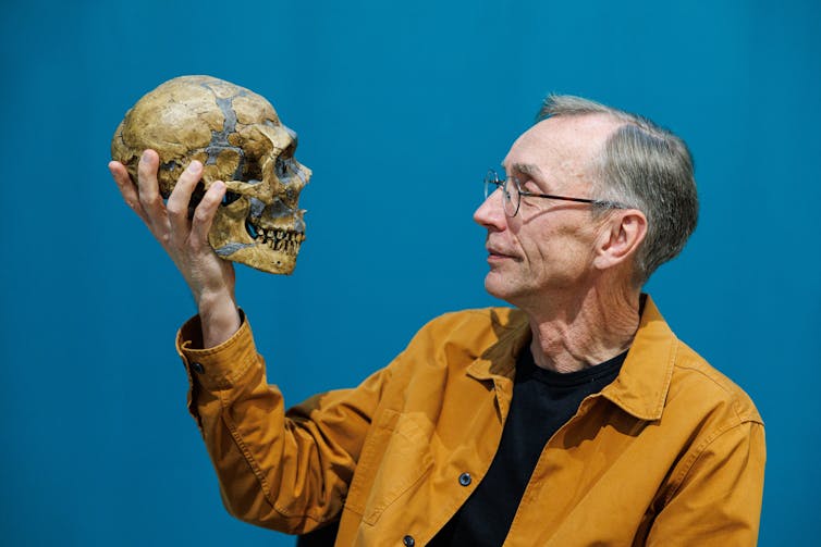 photo of man holding a human skull and looking at the face