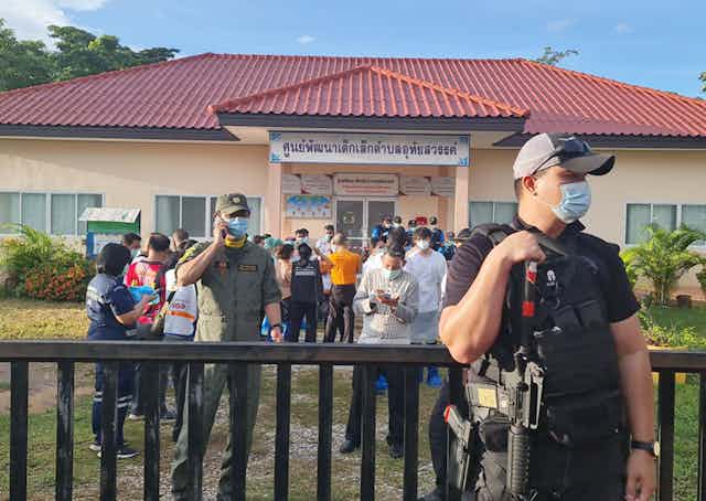 An armed guard outside a childcare centre where relatives of the victims of a massacre gather 