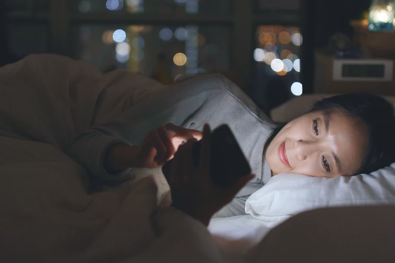 Woman in bed looking at her smart phone