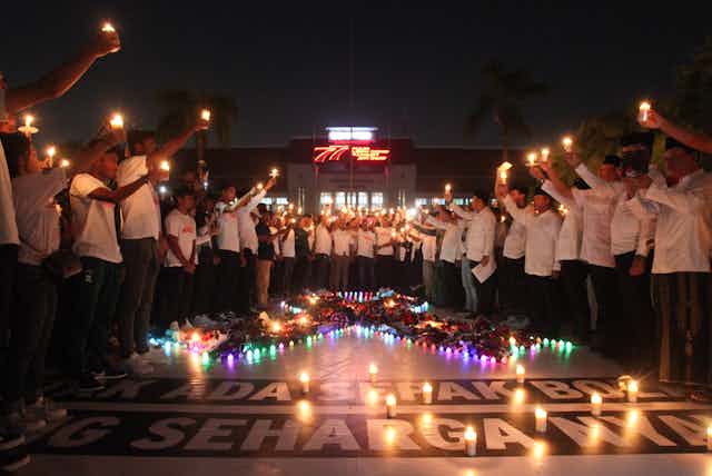Warga membawa lilin saat doa bersama di Balai Kota Surabaya, Jawa Timur, Selasa (4/10/2022) malam. Doa bersama itu untuk para korban tragedi kerusuhan di Stadion Kanjuruhan, Malang.
