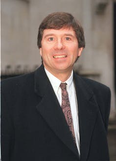 رجل يرتدي قميصًا أبيض وسترة سوداء.