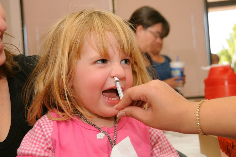 Girl receiving a nasal spray flu vaccine.