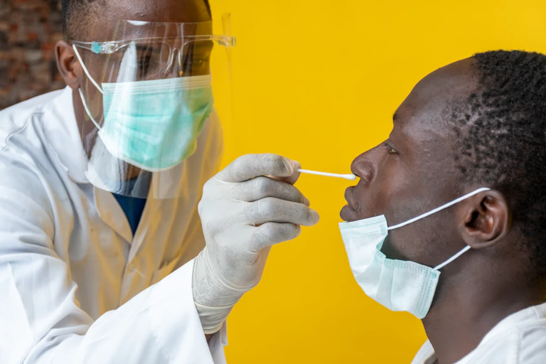 Un jeune médecin africain fait un prélèvement nasal à un homme noir.