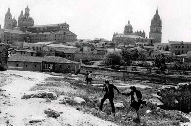 Una pareja pasea con la ciudad al fondo.