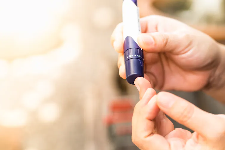 Gros plan des mains d’une femme utilisant une lancette sur un doigt pour vérifier le niveau de sucre dans le sang avec un glucomètre