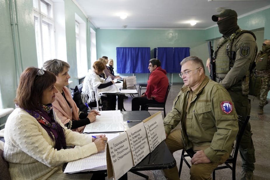 Le maire pro-russe de Mariupol accompagné d'un homme armé et masqué dans un bureau de vote