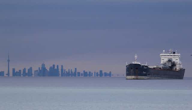 Un bateau navigue sur l'eau avec la ligne d'horizon de Toronto en arrière-plan.
