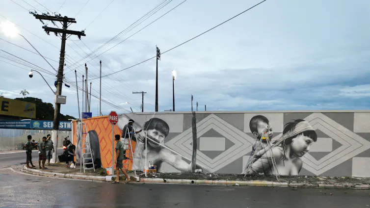 People paint a mural on a wall.