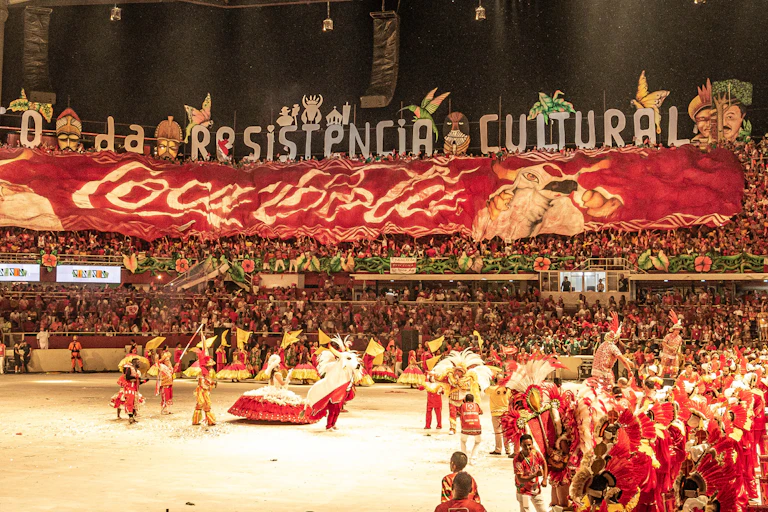 A stadium filled with people. Performers in red costumes are seen in the foreground.