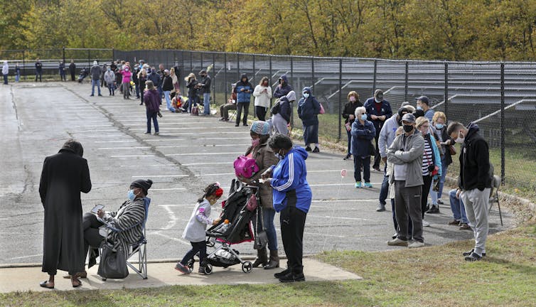 Hundreds of people dressed in winter jackets wait in line to vote.