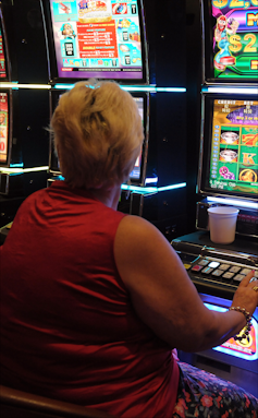 a woman sits at a poker machine