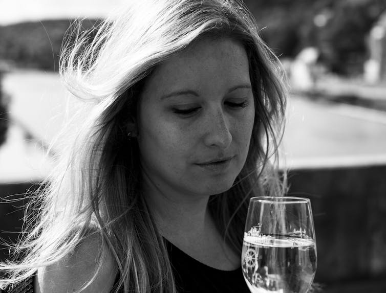 A woman looks at her wine glass.