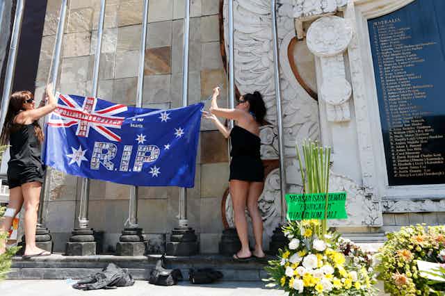 Relatives of victims of the 2002 Bali bombings hang an Australian flag at the memorial monument in Kuta, Indonesia.