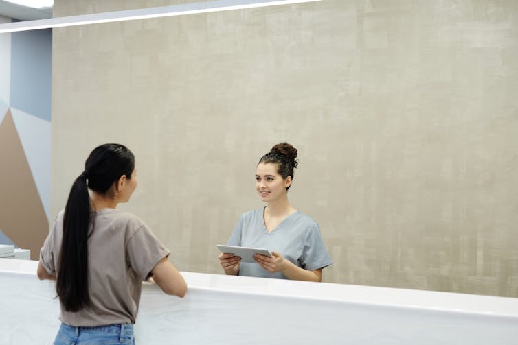 Patient talking to doctor receptionist or health staff behind desk