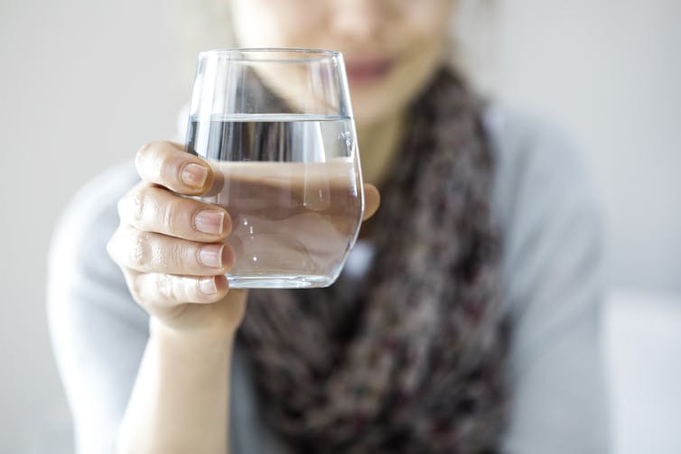 A woman holding a glass of water.