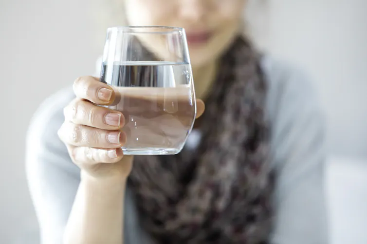 A woman holding a glass of water.