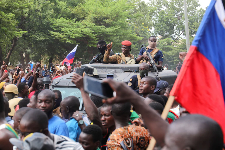 Captain Ibrahim Traore is welcomed by supporters holding Russian's flags as he arrives at the national television standing in an armoured vehicle in Ouagadougou, Burkina Faso October 2, 2022.