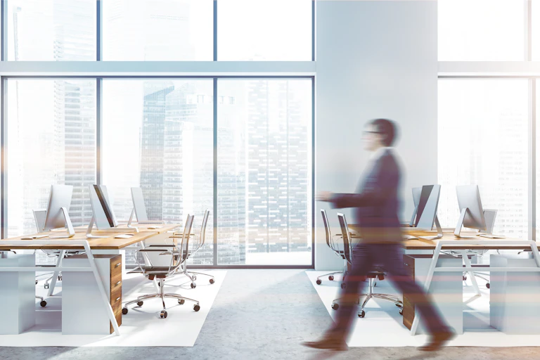 Empty office, one employee, blurred, view of skyscrapers.