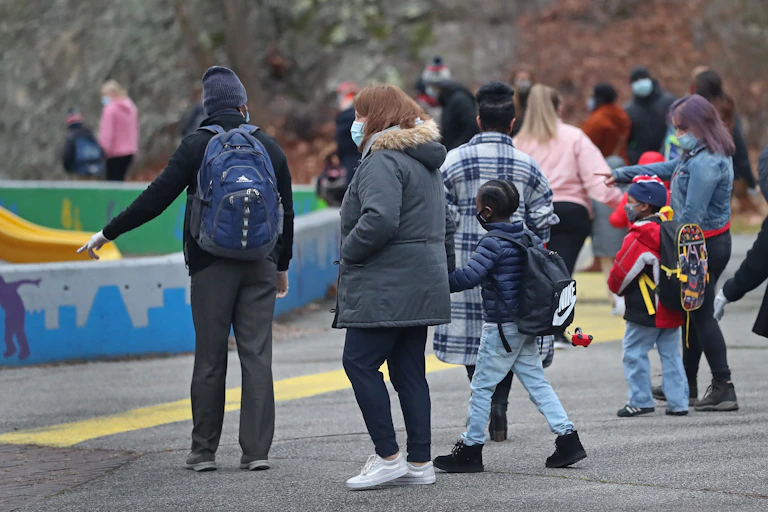 Adults and children gather in a schoolyard