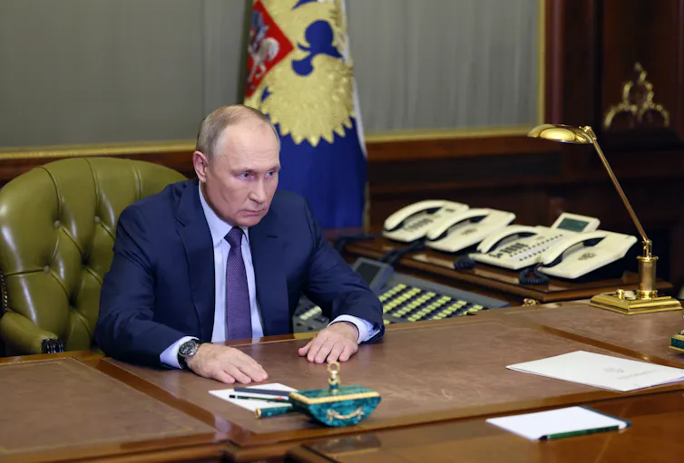 Vladimir Putin sitting at his des kin the Kremlin.