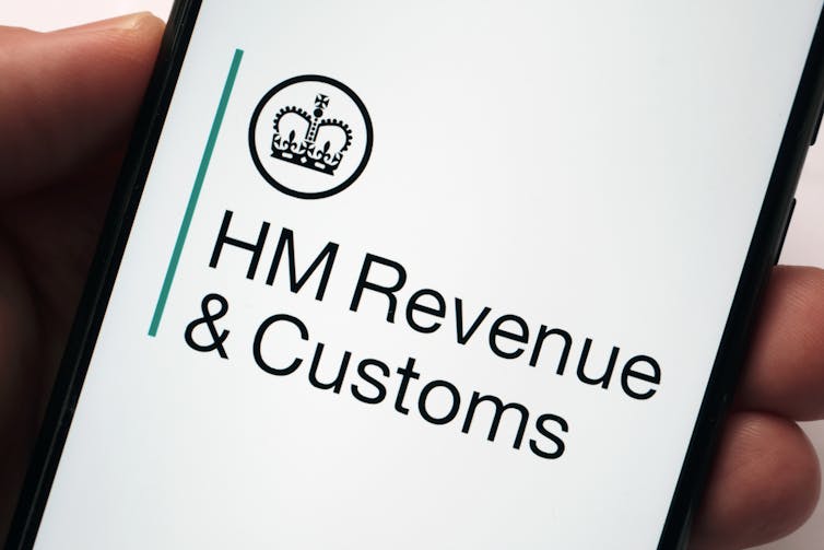 Hand holding phone with HM Revenue & Customs logo.