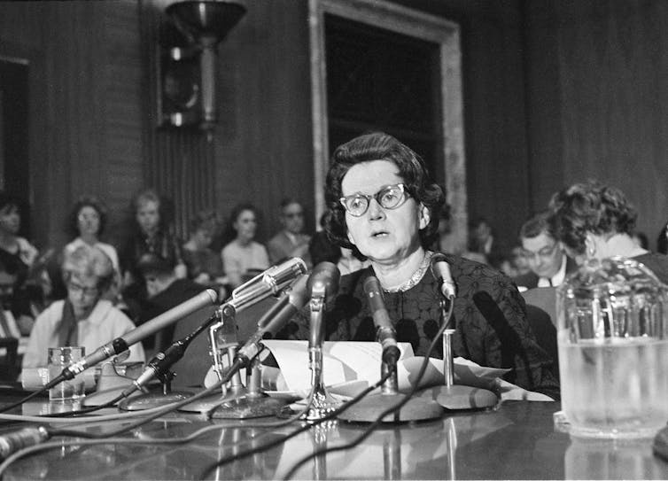 A woman seated at a microphone delivers a statement to a Congressional committee.