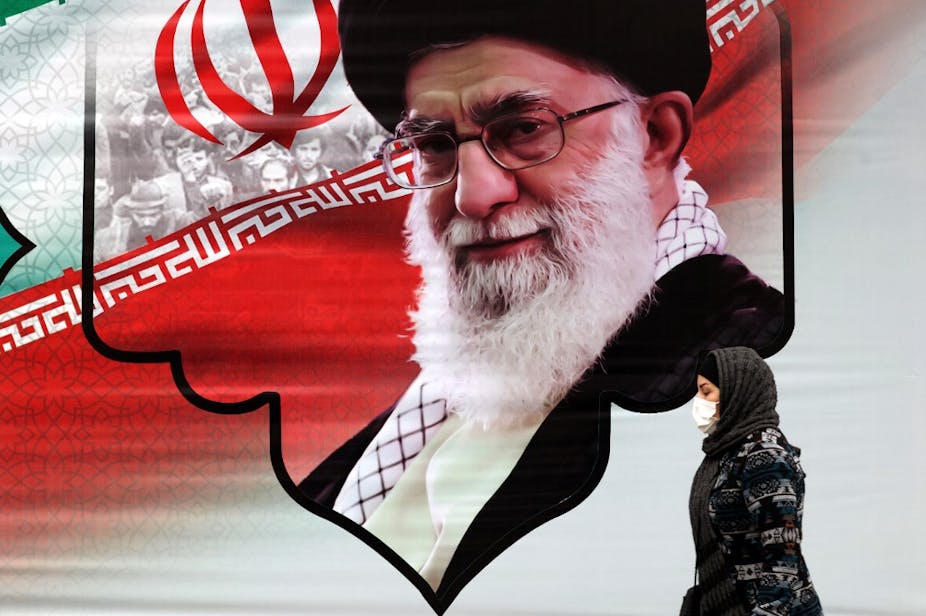Femme voilée passant devant un portrait d'Ali Khamenei