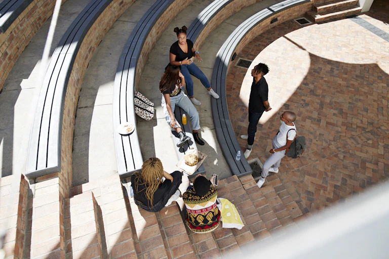 An aerial view taken with a fish-eye lens of six young people chatting in what appears to be a university auditorium