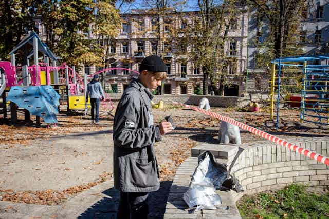 Kyiv, Ukraine. 10th Oct, 2022. A boy looks at a rocket fragment after a Russian missile attack in central Kyiv. 