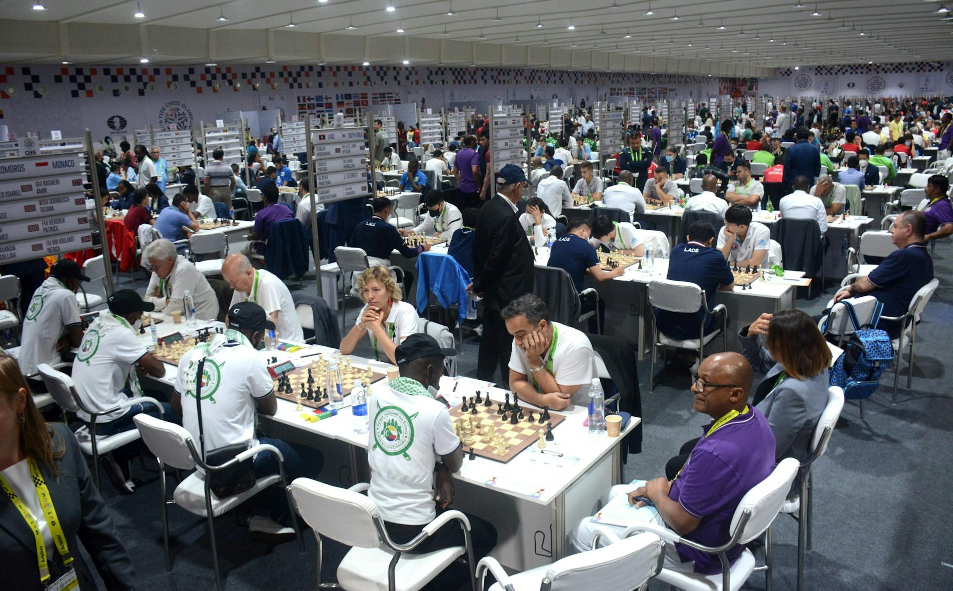 A large room filled with people sitting at tables playing chess.